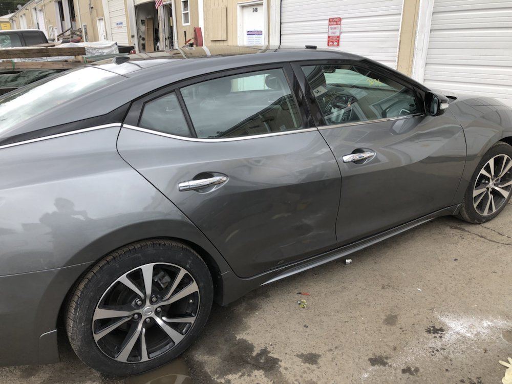 The same Nissan Maxima with repaired driver-side doors outside the shop