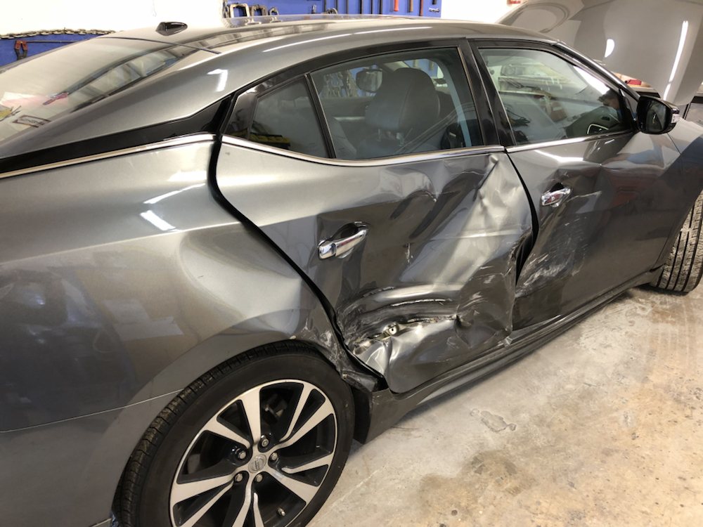Nissan Maxima with both driver-side doors damaged before repair